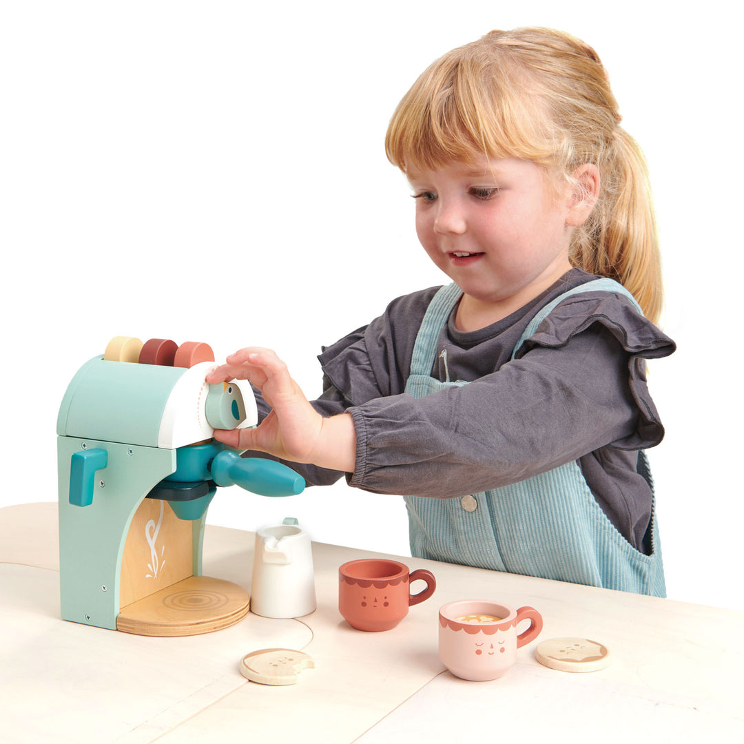 A young girl playing with a toy, wooden espresso maker